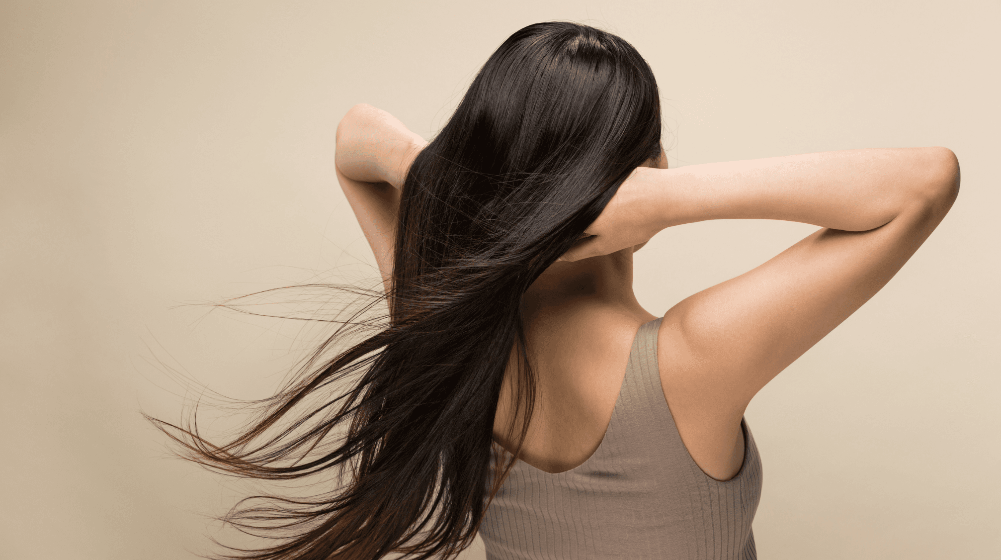 Gros plan sur une femme avec de longs cheveux sur fond beige.